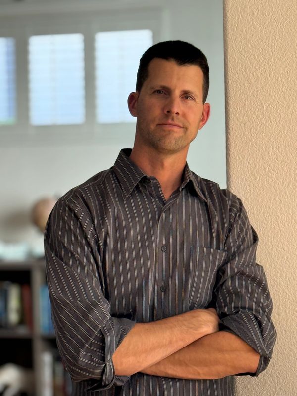 Man leaning against a wall with arms crossed.