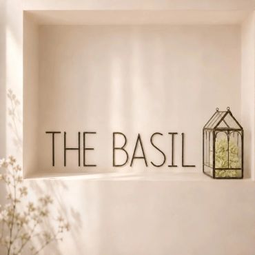 Minimalist wall sign reading 'THE BASIL' with a small glass terrarium.