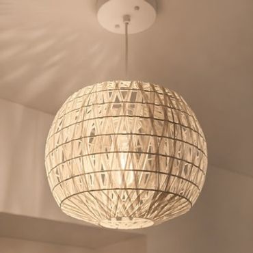 A spherical pendant light with a woven design emits a warm glow.
