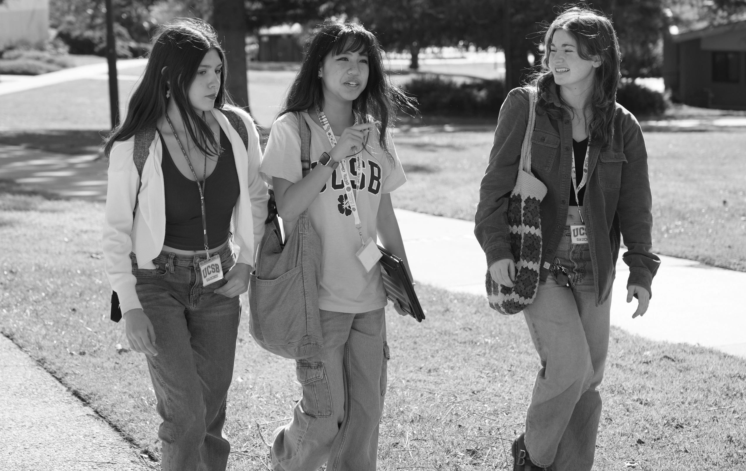 Three college students walking outdoors on a sunny day.