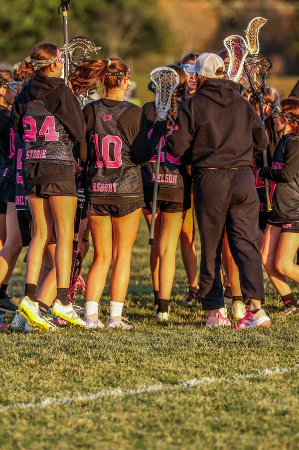 Girls' lacrosse team huddling during a game.