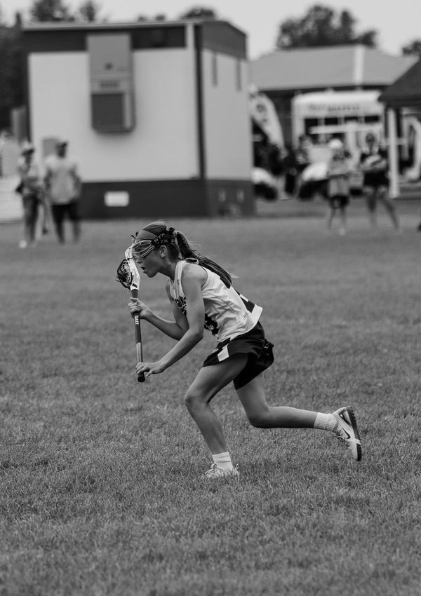 Girl playing lacrosse on a field.