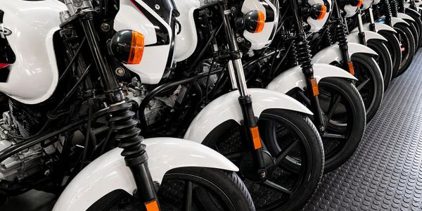 Row of identical white motorcycles neatly lined up indoors.