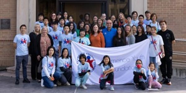 Group photo of diverse people holding a banner for a youth foundation.