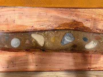 A wooden table with embedded colorful stones in resin.