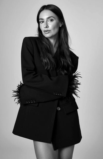 Portrait of a woman in an oversized black blazer with feather details.