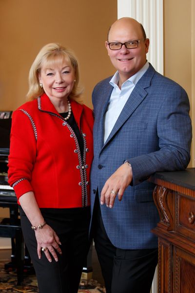 Smiling man and woman posing indoors in formal attire.