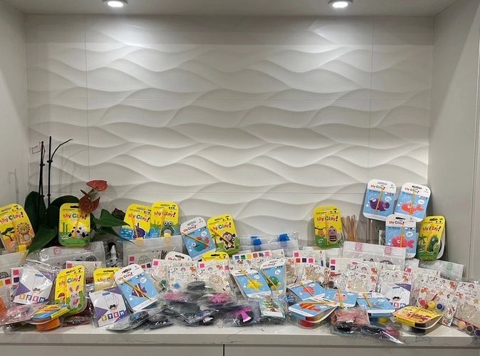 A countertop filled with various colorful kids' craft and STEM kits against a textured white backsplash.