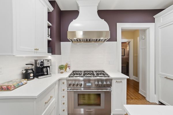 Modern kitchen with stainless steel stove and white cabinetry.