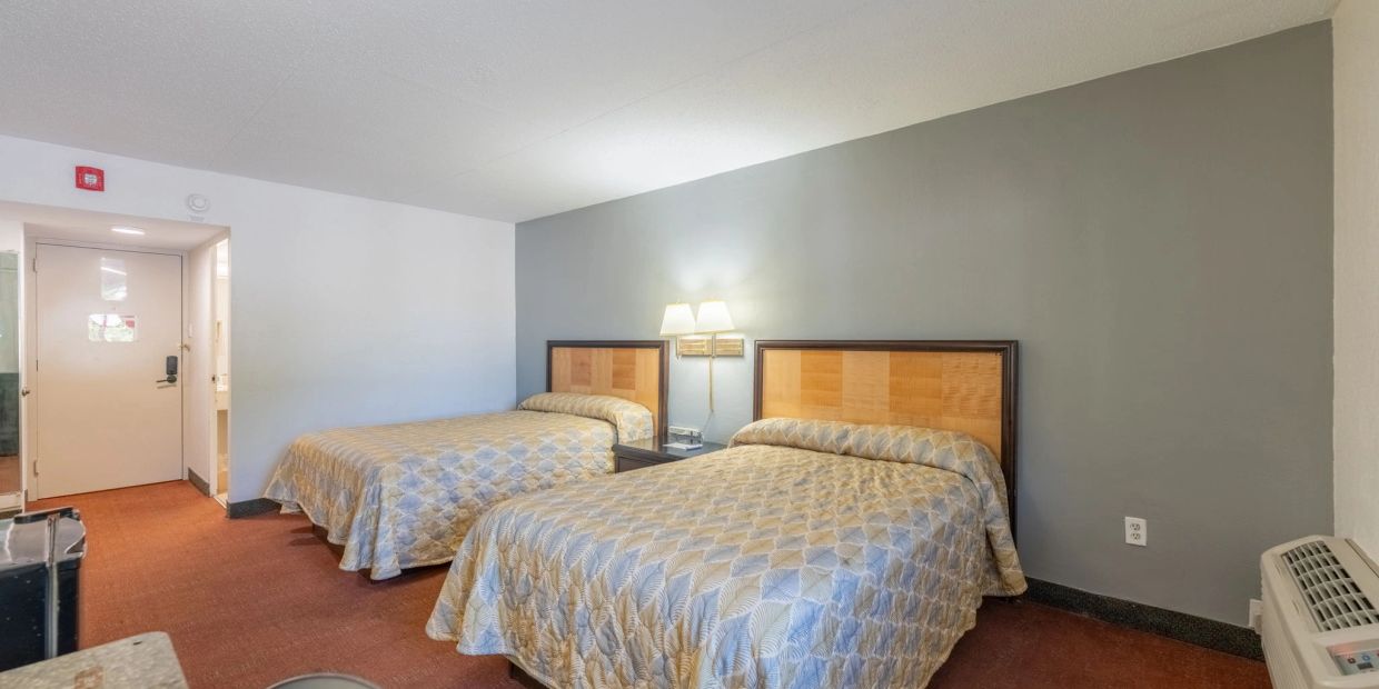 Hotel room with two queen beds and beige decor.