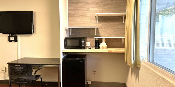 Simple kitchenette with TV, table, microwave, and mini-fridge.