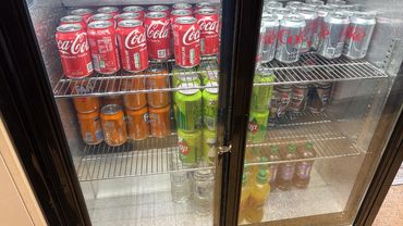 Fridge stocked with soda cans and bottles.