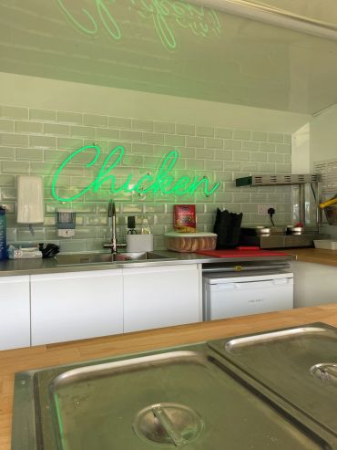 Neon sign reading 'Chicken' in a kitchen.