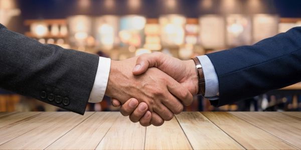Two people shaking hands in a business setting.