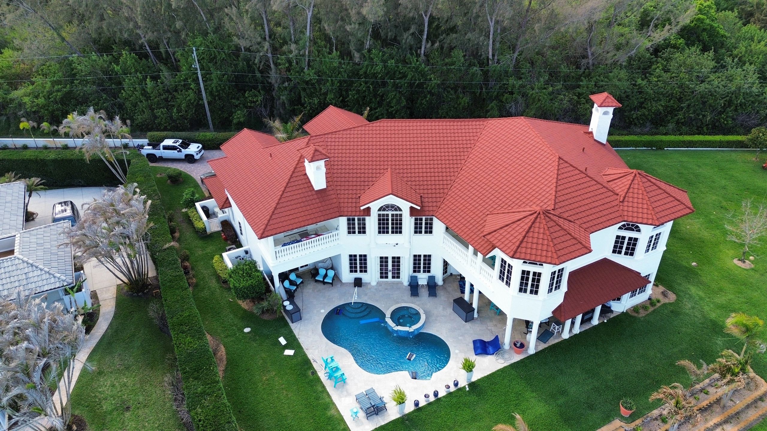 A large white house with a red tiled roof and a swimming pool in the backyard.