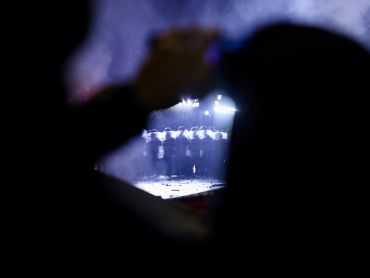 Silhouetted person watching a line of riot police at night.