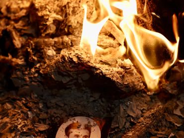 A burning photograph of a man amidst flames and ashes.
