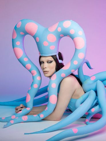 Model wearing a blue and pink octopus costume with tentacles and gloves.