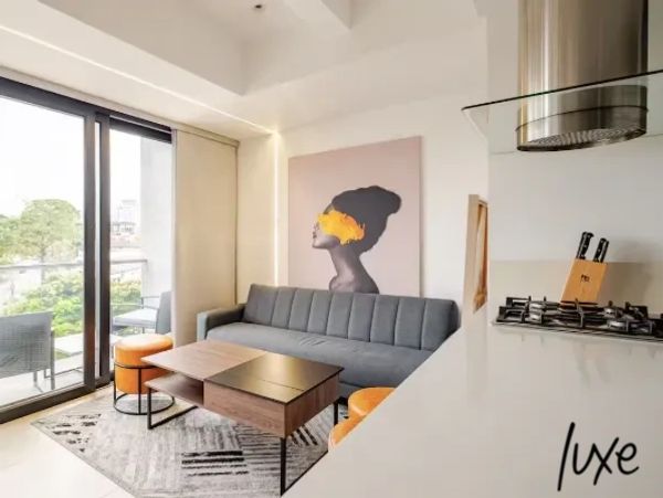 Modern living room with gray sofa, artistic wall painting, and balcony view.
