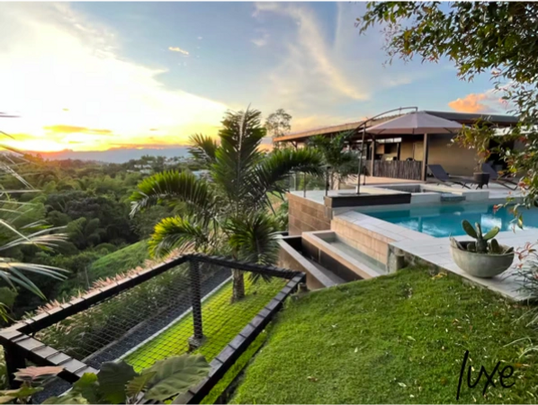 Luxurious outdoor pool area overlooking lush greenery during sunset.