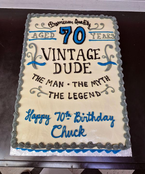 A birthday cake celebrating a 70-year-old named Chuck, decorated with vintage-themed text.