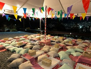 Área al aire libre con cojines y decoraciones coloridas bajo una carpa.
