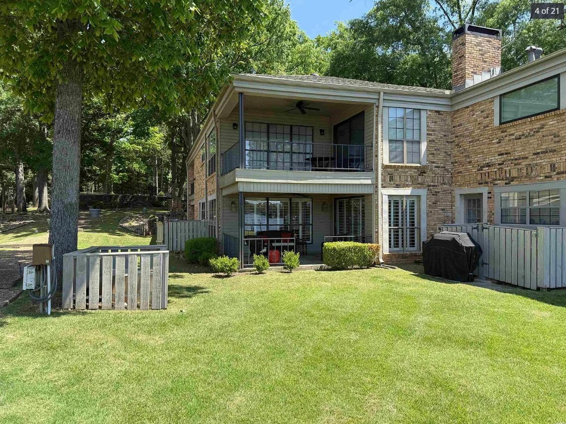 Two-story brick house with covered porch and lush lawn on a sunny day.