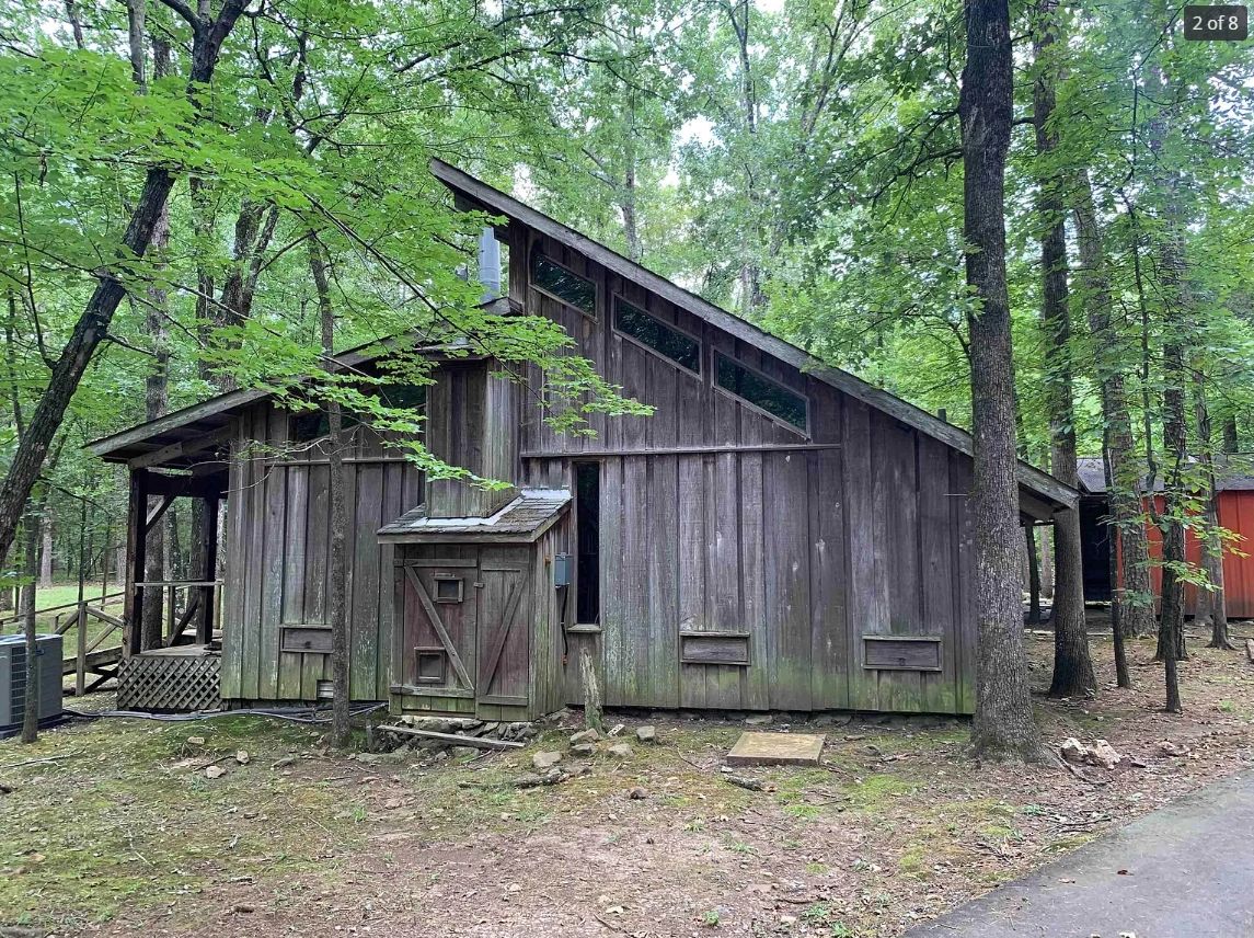 Rustic wooden cabin surrounded by trees in a forest setting.