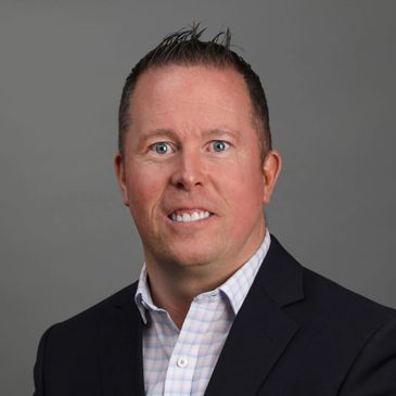 Professional headshot of a man in a suit with a gray background.
