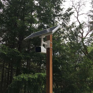 Outdoor solar powered security camera mounted on pole for remote cellular access on commercial farm.