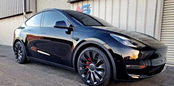 A Tesla Model is parked outside a contemporary building, highlighting the premium experience