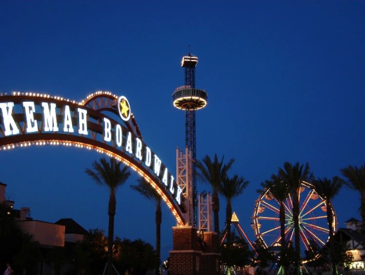 Kemah Boardwalk entrance lit up at night with amusement rides in the background.