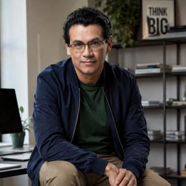 Man sitting on a stool in a modern office setting.