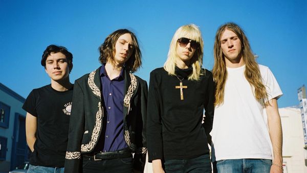Four young adults posing outdoors against a clear blue sky.