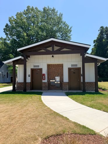 Small public restroom building with two doors and a water fountain outside.