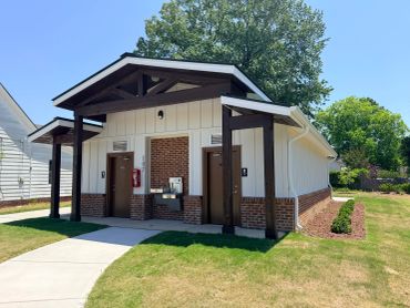 Modern public restroom building in a park with brick and wood accents.