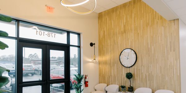 Modern waiting area with light wood wall and white chairs.