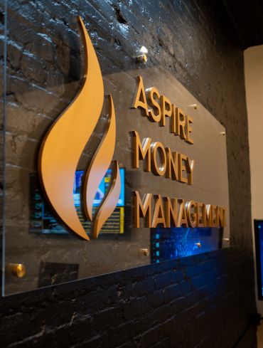 Sign for Aspire Money Management on a dark brick wall.