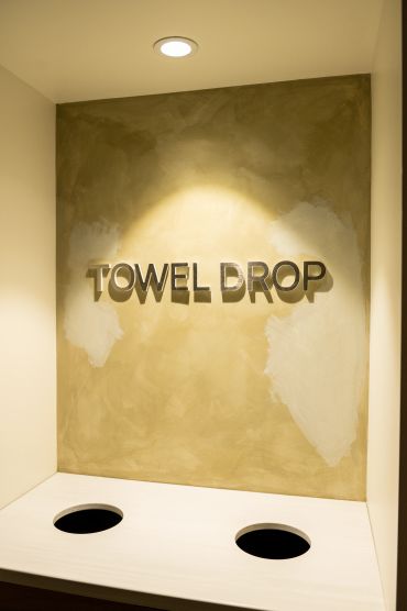 Wall with "Towel Drop" sign and two holes for towels.