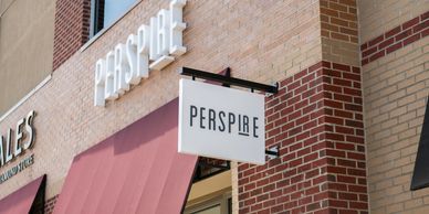 Storefront sign reading "PERSPIRE."