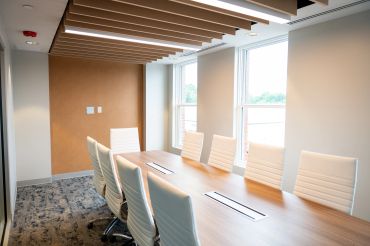 Modern conference room with white chairs and wood table.