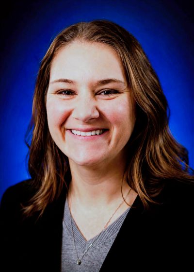 Smiling woman with brown hair against blue background.