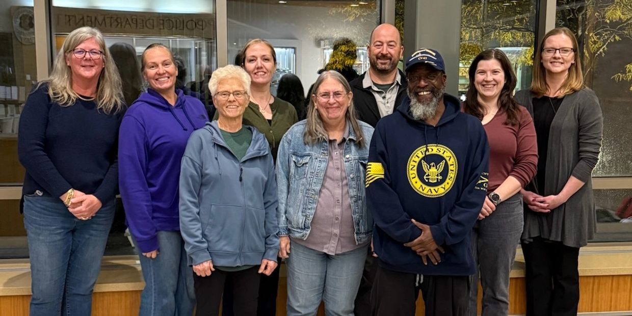 Image: Group smiling. Nine people in total.
 7 women and 2 Men.