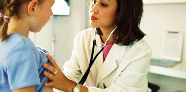 Doctor examining a young girl with a stethoscope.