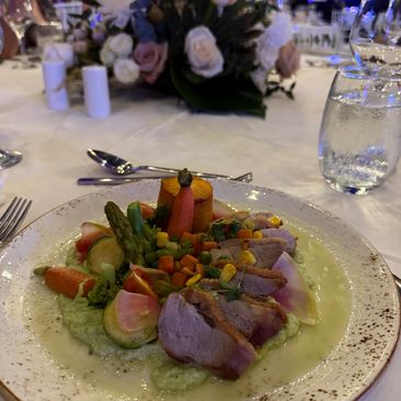 A gourmet plate with sliced meat and colorful vegetables.