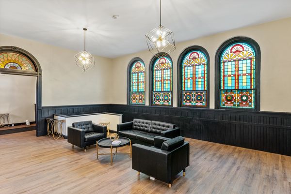 Modern seating area with stained glass windows and geometric pendant lights.