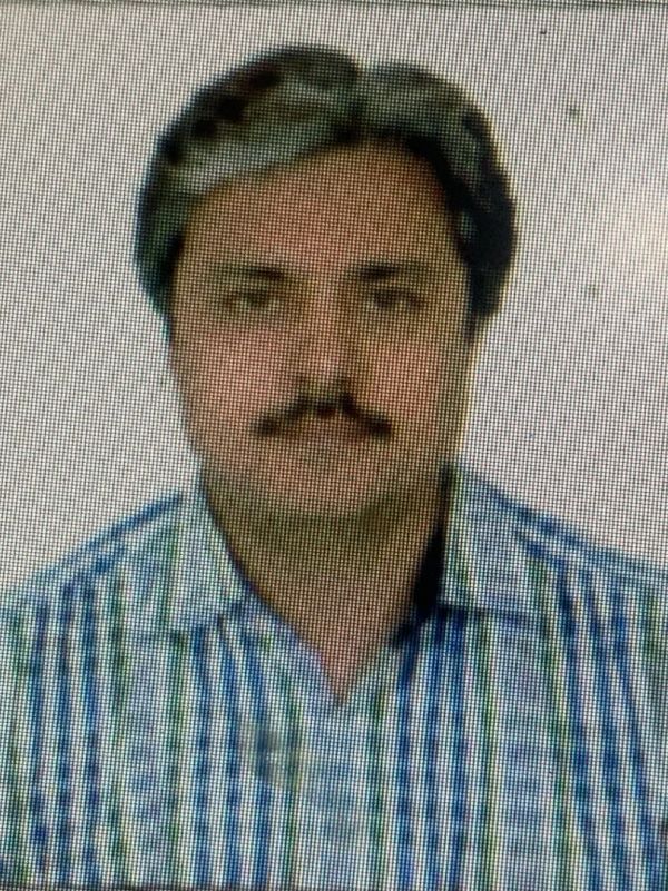 Portrait of a man with a mustache wearing a checkered shirt.