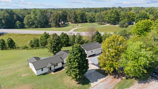 Aerial view of a white house with multiple trees and a driveway.