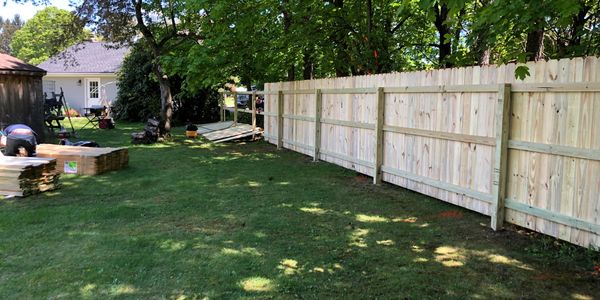 Newly installed wooden privacy fence in a sunny backyard.