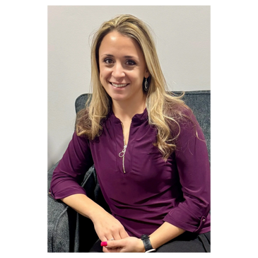 Smiling woman with blonde hair in a purple blouse sitting on a chair.